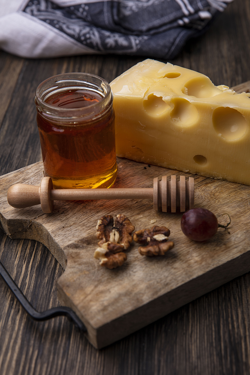 side view honey in a jar of cheese and walnuts with grapes on a